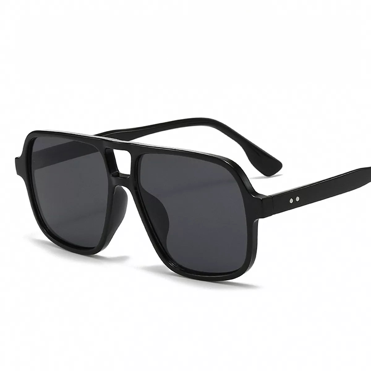 Black oversized aviator sunglasses with smoky gray lenses, a cutout bridge, and two small silver-tone dots on the temple against a white background