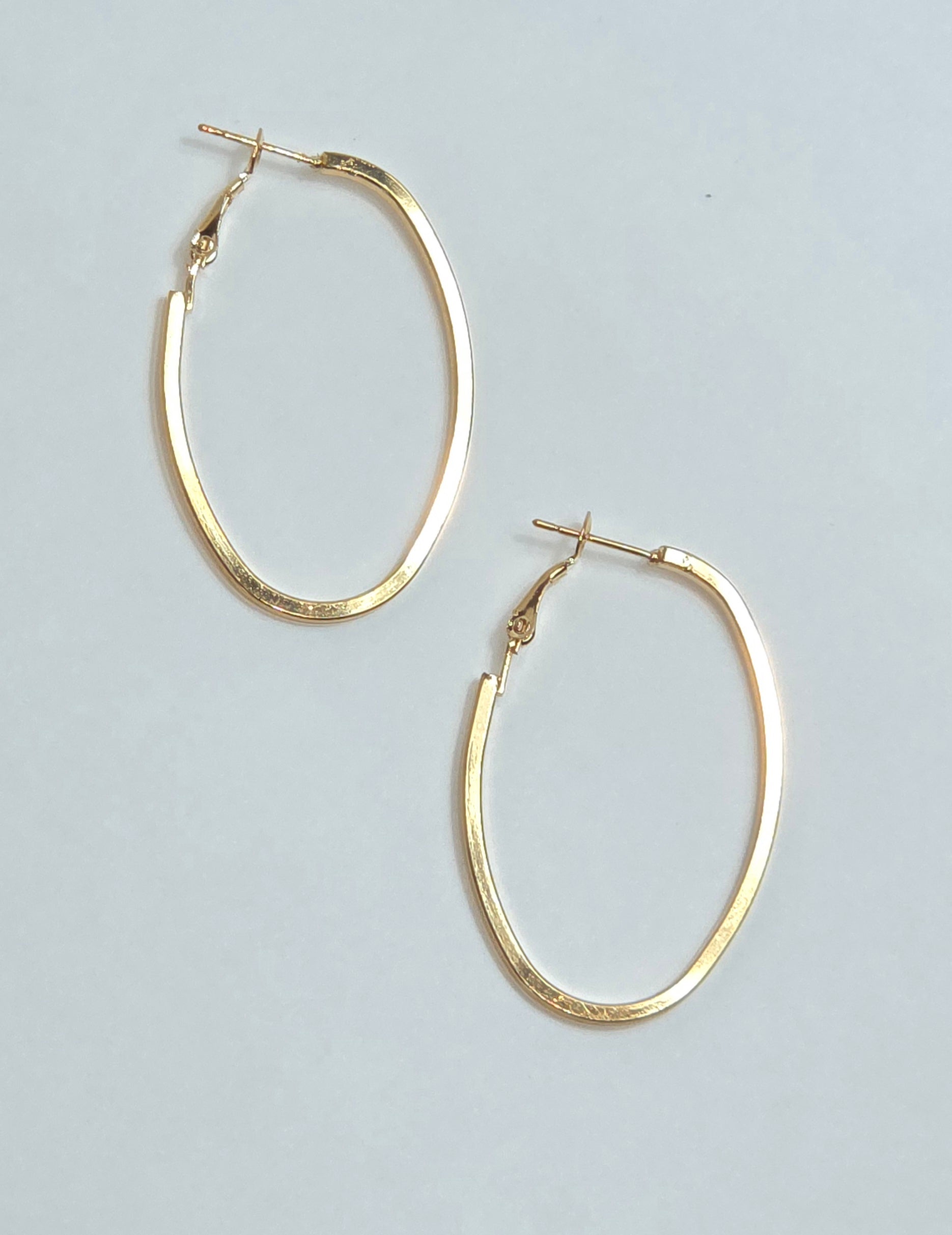 A pair of textured gold hoop earrings with post-back closures, displayed on a light gray background.