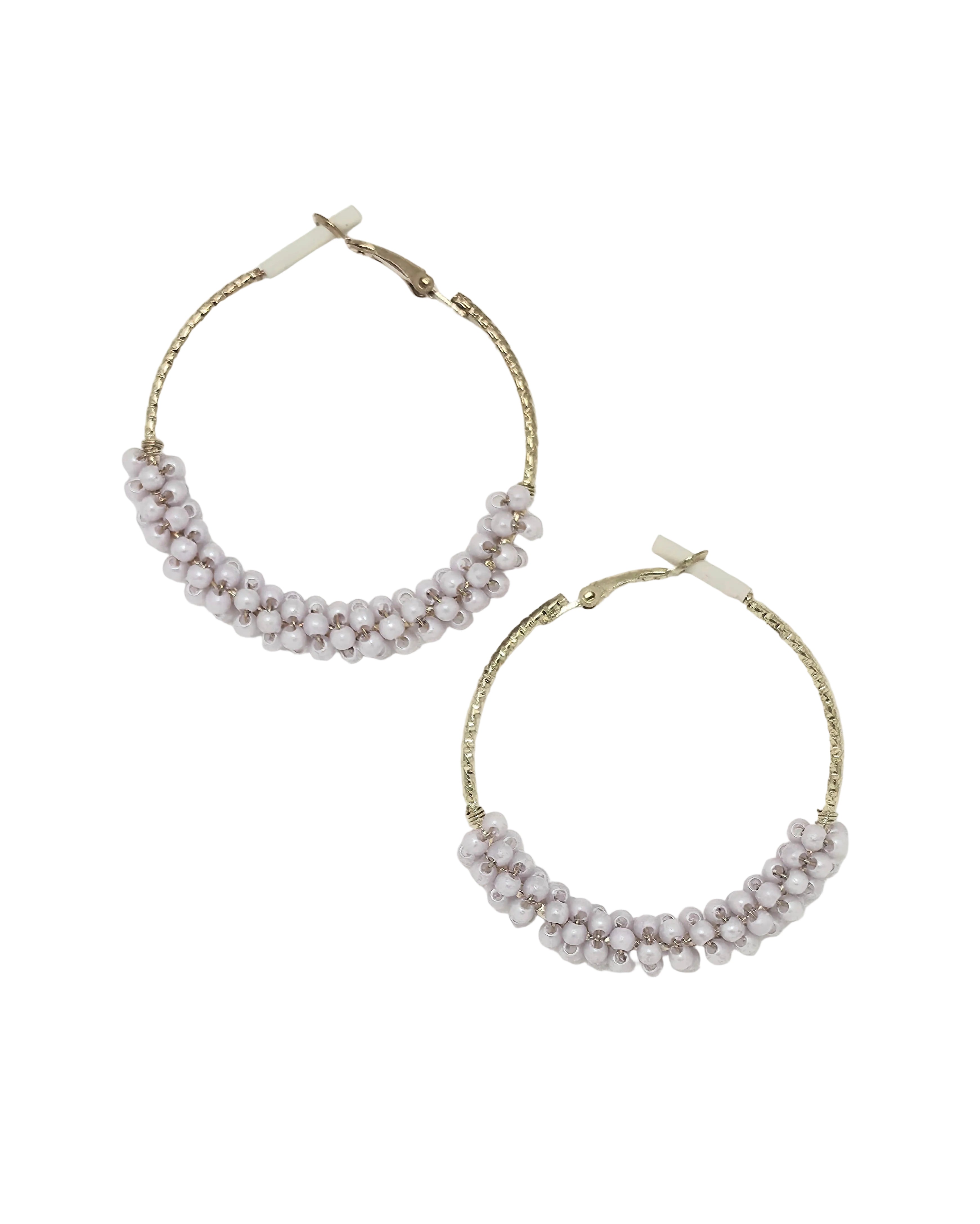 Pair of gold-tone textured hoop earrings with chunky lavender pink crystal beads wire-wrapped along the bottom half, hinged click-top closure, isolated on white background