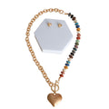 Chunky multi-color bead and gold cable chain heart toggle necklace with gold heart stud earrings on white hexagonal display stand, white background
