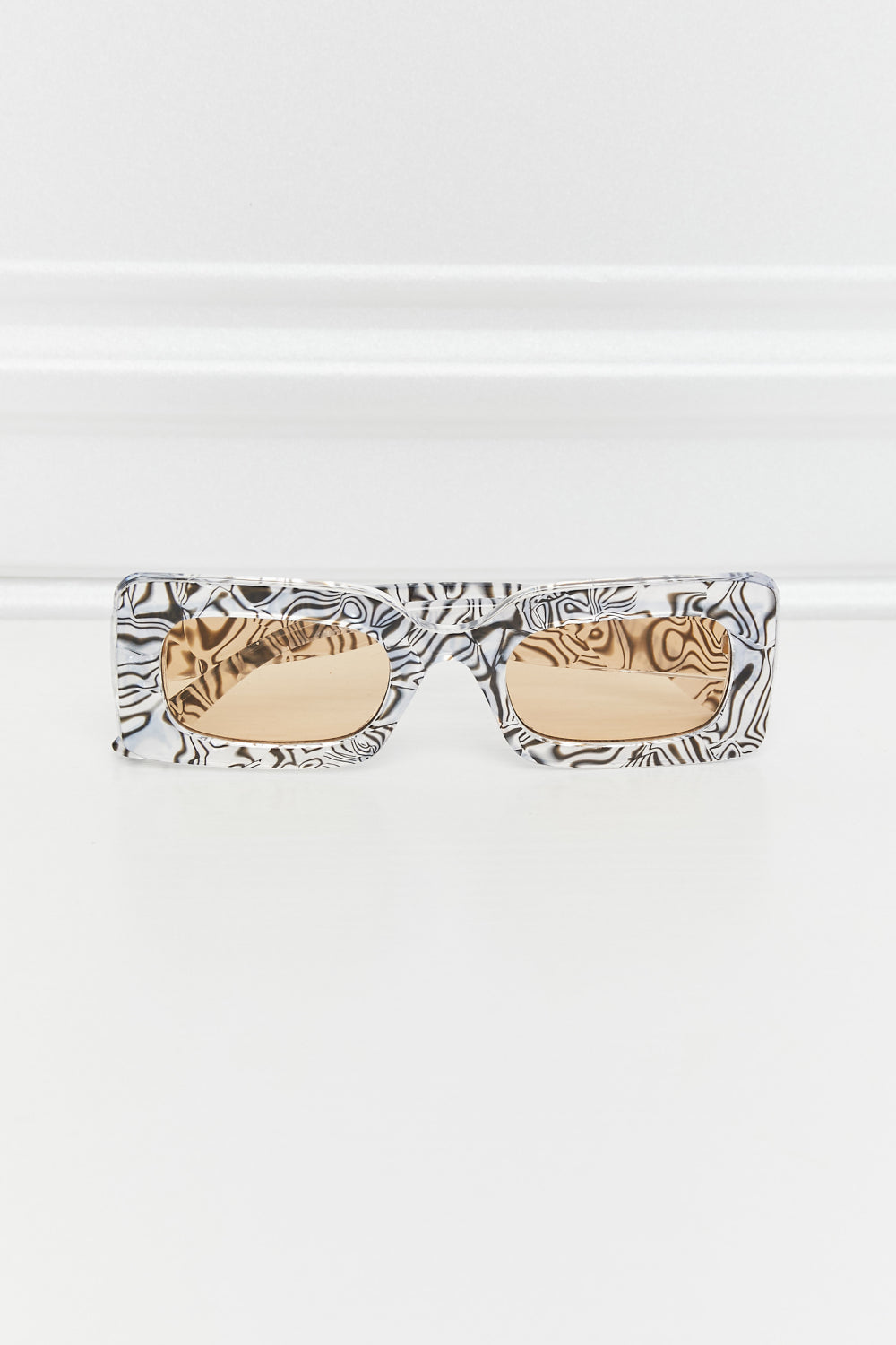Front view of Zebra rectangle sunglasses with black-and-white swirled frames and warm-tinted lenses