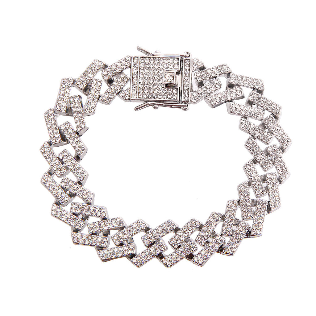 Overhead flat lay of a wide chunky fully pave clear rhinestone square Cuban chain link bracelet in rhodium silver tone arranged in a circle on a white background. A large square rhinestone-crusted flip lock box clasp with a hinged safety bar is visible at the top, fully covered in clear rhinestones.