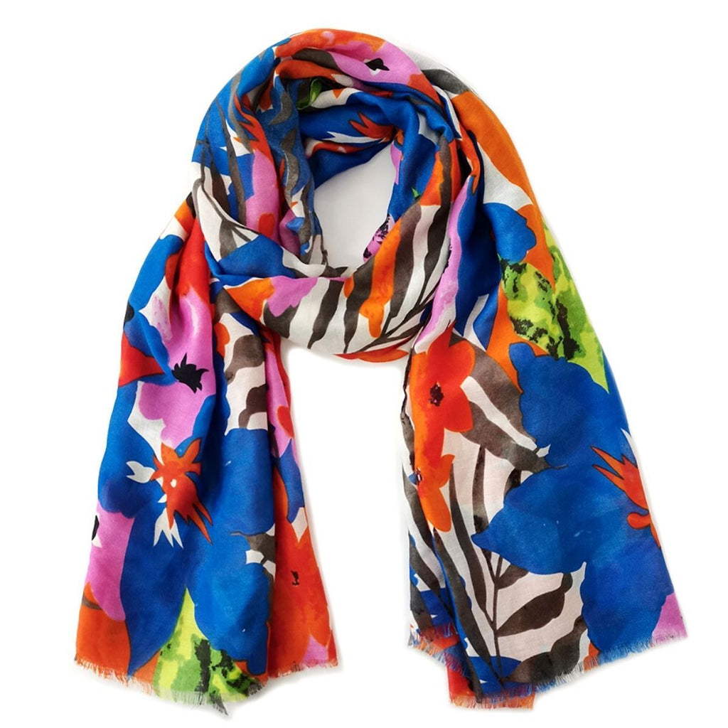 Blue-and-orange watercolor floral scarf loosely looped against a white background, showing pink flowers, green accents, dark leafy strokes, and fine frayed ends