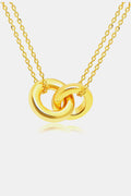 Close-up of two polished gold-tone interlocking ring pendants suspended from delicate oval-link chains against white