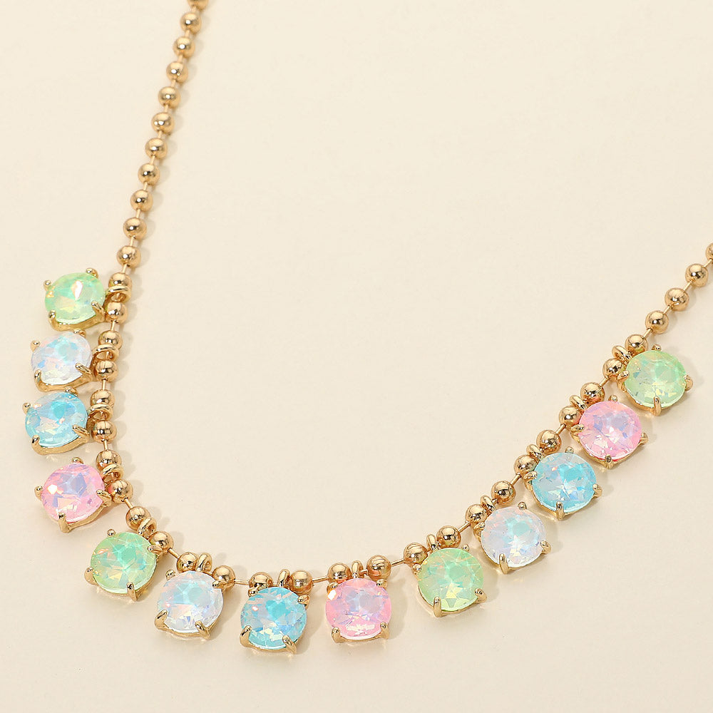 Close-up of opal multi-tone pastel round faceted stones in gold prong settings on gold ball chain link necklace — detail shot showing pink, mint green, and sky blue iridescent stone colors on cream background