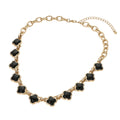 Women's black quatrefoil stone gold bold twisted link chain necklace flat lay showing full length, gold oval link chain, adjustable extender with ball tip, and lobster clasp — white background