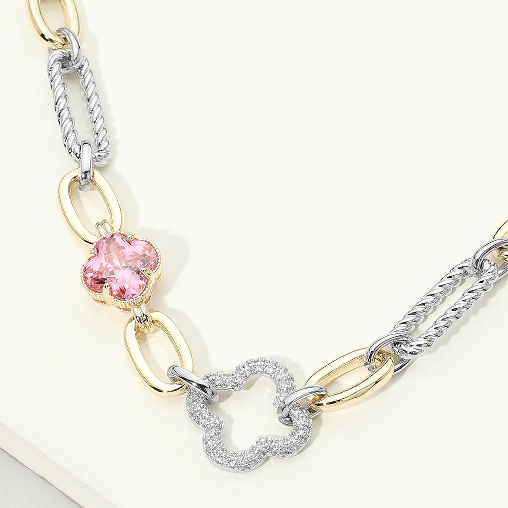 Close-up of 14K gold CZ pavé clover mixed link necklace on cream background showing pink faceted clover stone in gold prong setting, open CZ pavé silver clover pendant, and alternating gold oval and silver twisted rope links
