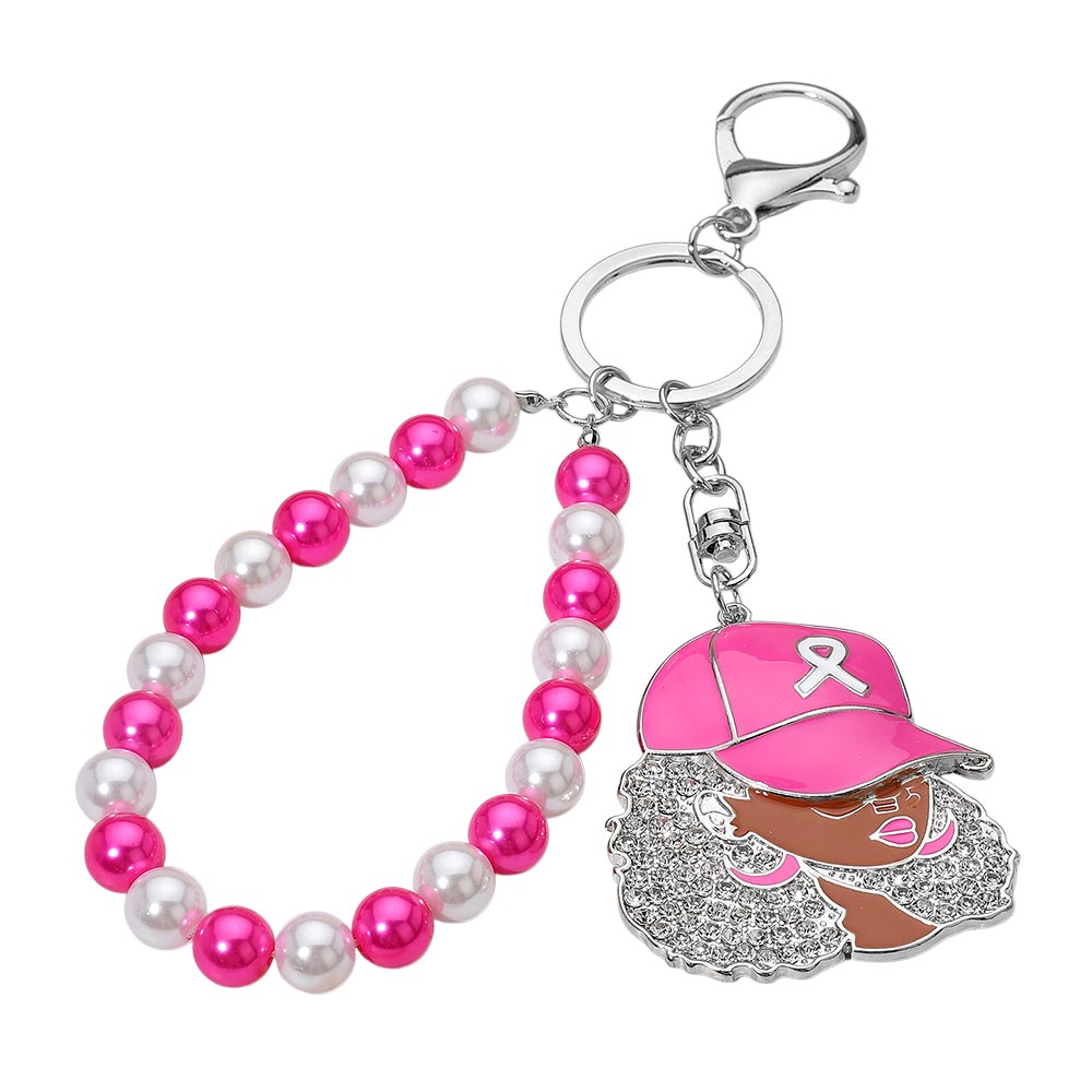 A pink and white beaded phone strap keychain with a dangling charm of a woman in a pink cap with a breast cancer ribbon, set against a plain white background.
