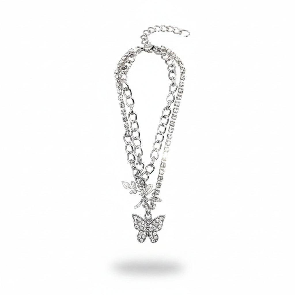 Rhinestone pavé butterfly charm layered chain anklet in silver-tone — curb chain layer and clear crystal rhinestone tennis chain layer, rhinestone pavé butterfly pendant with silver leaf charm accent, silver lobster clasp and extender chain, white background
