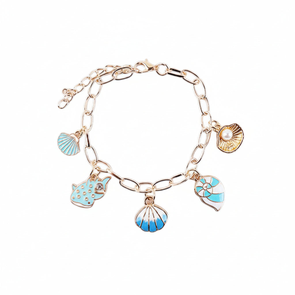 Ocean seashell charm station bracelet in gold-tone — gold paperclip link chain with lobster claw clasp and extender chain, 5 dangling enamel charms: teal enamel starfish, white pearl bead, teal enamel dolphin, blue and white striped scallop shell, and teal and white ribbed scallop shell, white background
