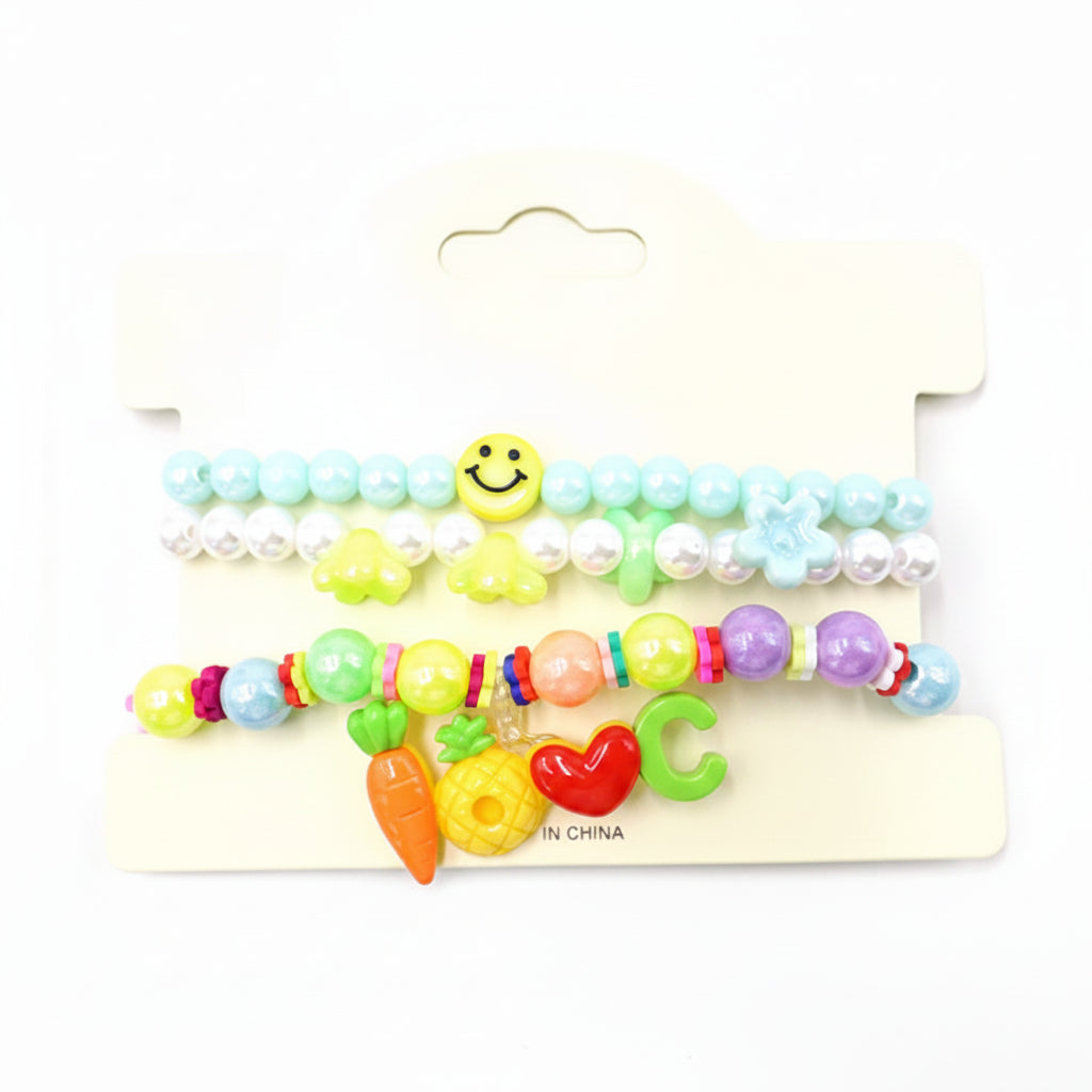 Kids charm beaded stretch bracelet set in mint blue and yellow — 3-piece stackable set with light blue bead bracelet with smiley face, pearl bead bracelet with star and flower charms, and LOVE charm bracelet with carrot, pineapple, heart, and letter charms, cream retail card, white background