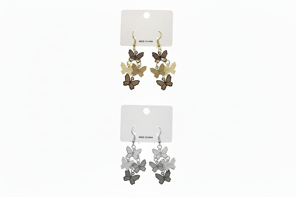 Two pairs of butterfly metal plate layered drop earrings on white retail cards — top pair in gold-tone with cascading cluster of dark brown, tan, and cream butterfly charms on fish hook backs; bottom pair in silver-tone with cascading cluster of charcoal, gray, and white butterfly charms on fish hook backs, white background