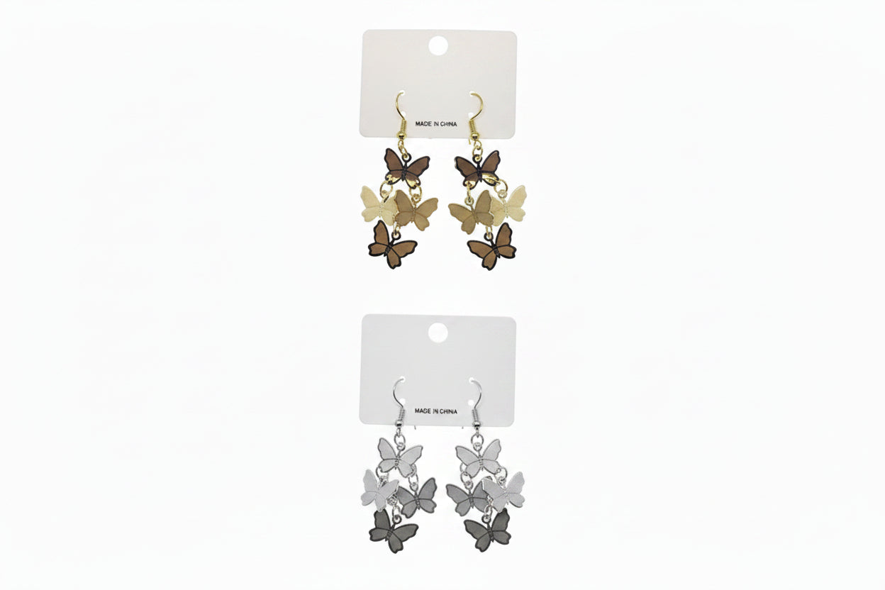 Two pairs of butterfly metal plate layered drop earrings on white retail cards — top pair in gold-tone with cascading cluster of dark brown, tan, and cream butterfly charms on fish hook backs; bottom pair in silver-tone with cascading cluster of charcoal, gray, and white butterfly charms on fish hook backs, white background