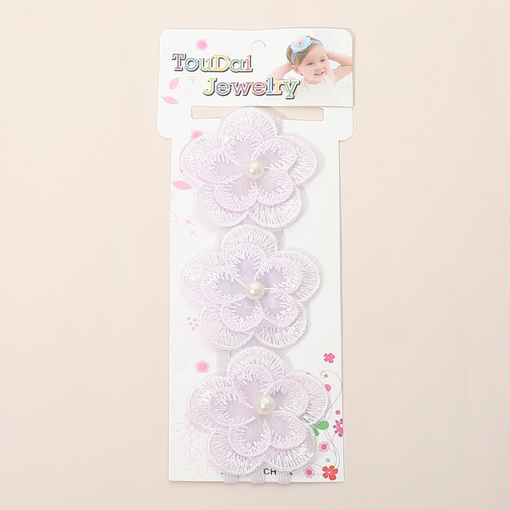 Kids floral lace stretch headband in light blue on light blue floral retail card — three layered light blue lace flower accents with pearl bead centers, white background