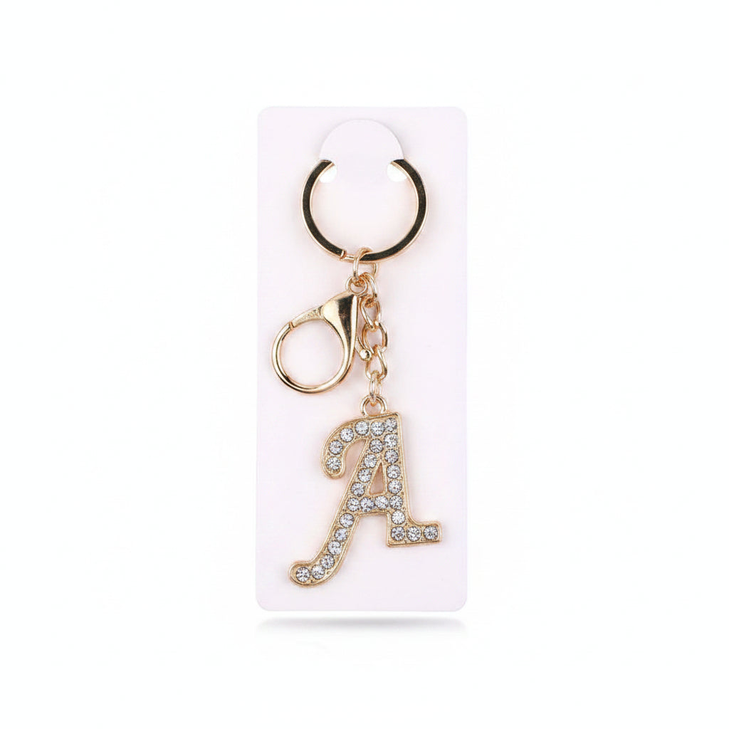 Rhinestone pavé initial letter A keychain bag charm with clear crystal rhinestone pavé script A pendant, gold-tone lobster clasp and key ring, displayed on white retail card, white background