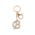 Rhinestone pavé initial letter B keychain bag charm with clear crystal rhinestone pavé script B pendant, gold-tone lobster clasp and key ring, gold chain link, white background