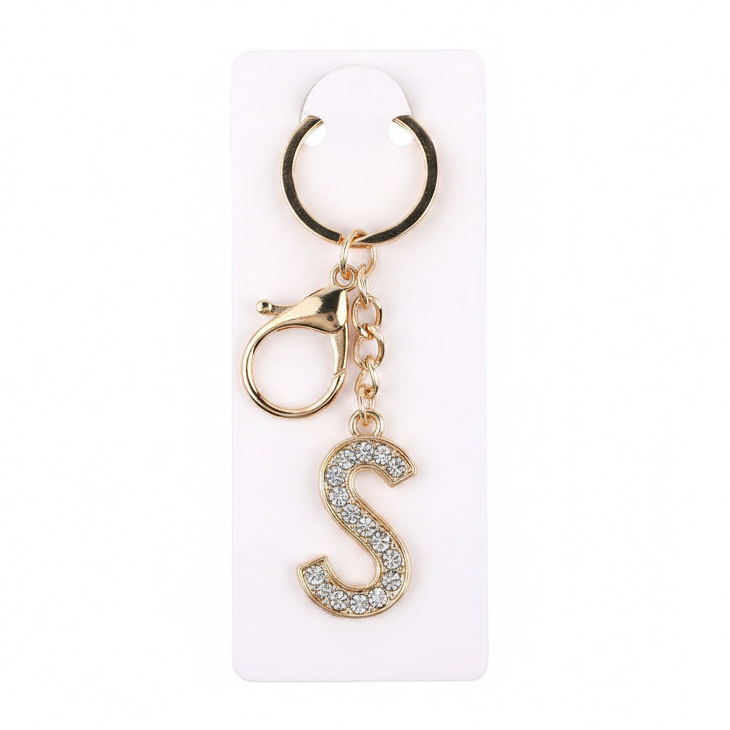 Rhinestone pavé initial letter S keychain bag charm with clear crystal rhinestone pavé block S pendant, gold-tone key ring and lobster clasp with gold chain link, displayed on white retail card, white background