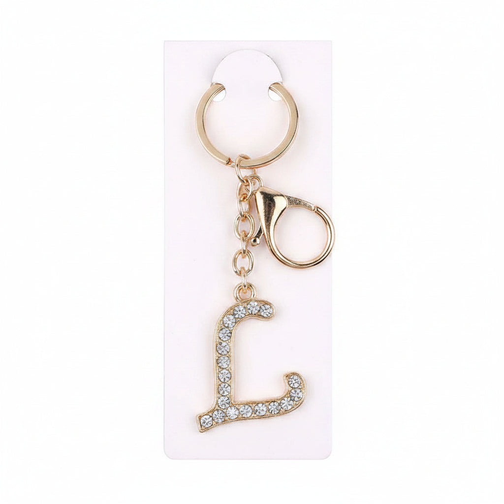Rhinestone pavé initial letter L keychain bag charm with clear crystal rhinestone pavé L pendant, gold-tone lobster clasp and key ring, displayed on white retail card, white background