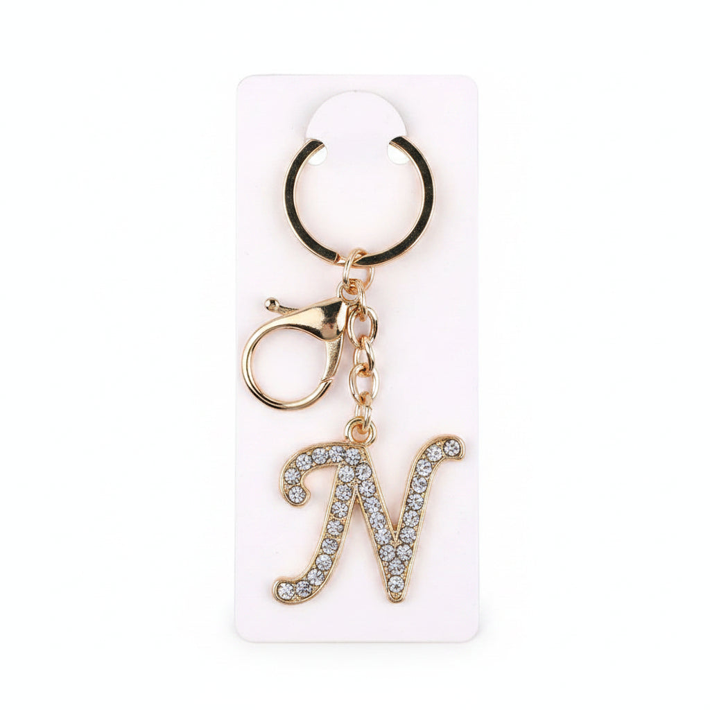 Rhinestone pavé initial letter N keychain bag charm with clear crystal rhinestone pavé script N pendant, gold-tone lobster clasp and key ring, displayed on white retail card, white background