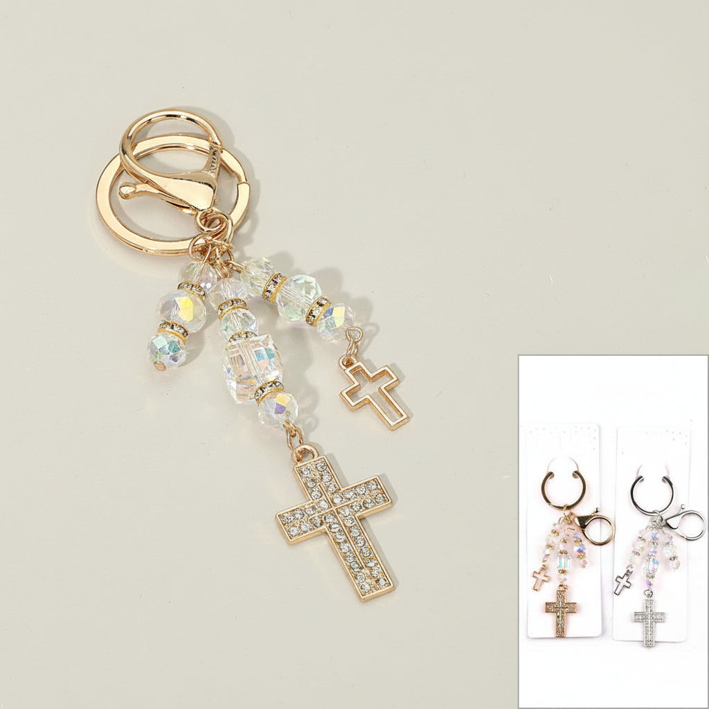 Double rhinestone cross charm drop bag charm keychain with iridescent AB crystal faceted beads, gold-tone open cross and pavé rhinestone cross pendants on warm beige background, with inset showing both gold and silver colorways on retail display cards