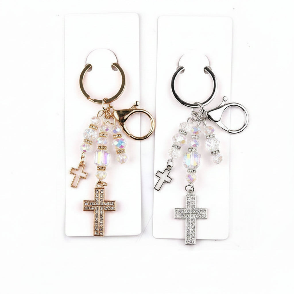 Two double rhinestone cross charm drop bag charm keychains displayed on white retail cards — gold-tone version on left and silver-tone version on right, both with iridescent AB crystal faceted beads and double cross pendants