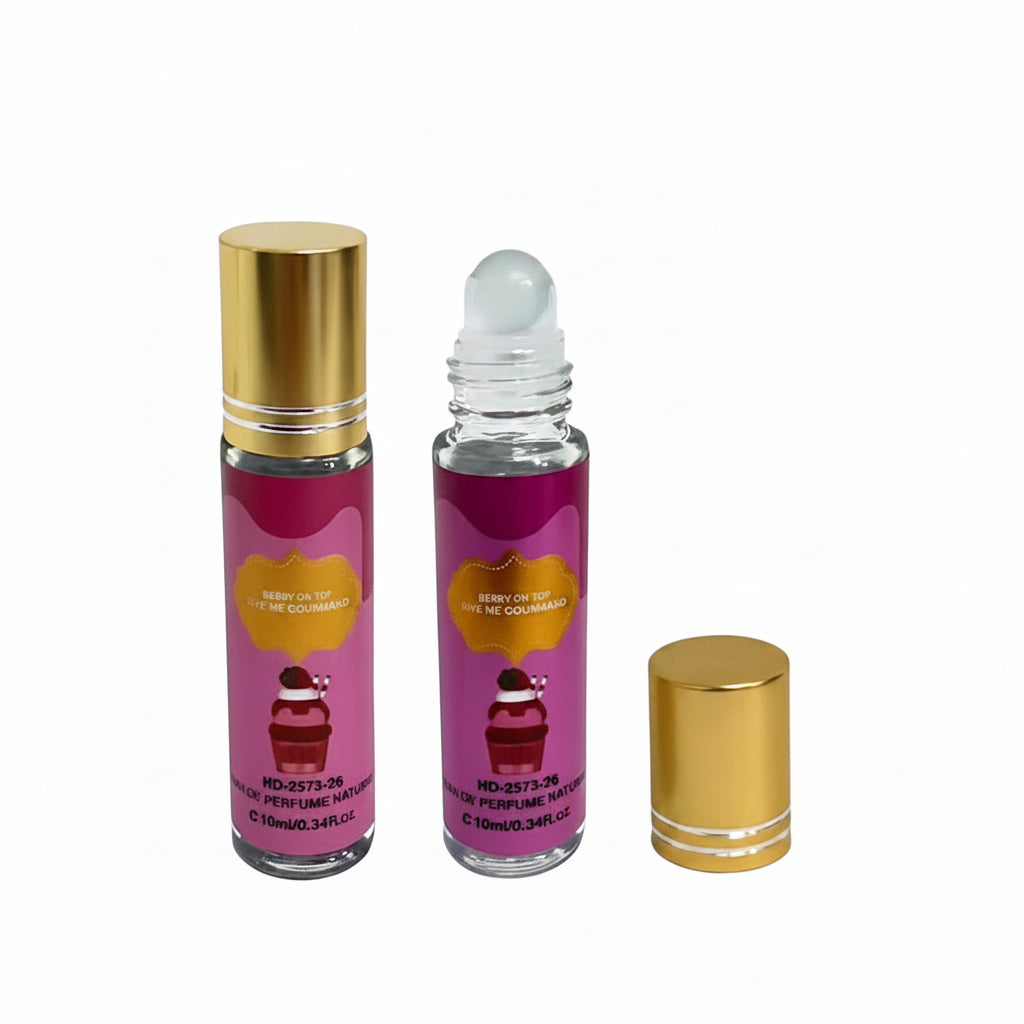 Two 10ml mini eau de parfum roll-on bottles with pink "Berry on Top Give Me Gourmand" labels — one capped in gold, one showing clear roller ball applicator — with detached gold cap beside them, white background