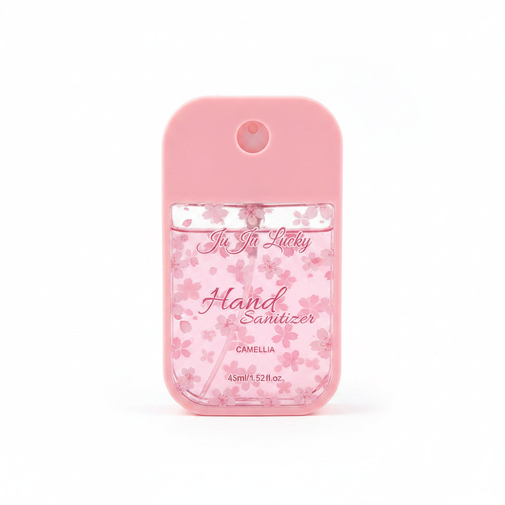 Ju Ju Lucky pocket hand sanitizer spray 45ml in light pink silicone case with pink cherry blossom floral print label reading Ju Ju Lucky Hand Sanitizer Camellia 45ml/1.52fl.oz, circular spray nozzle on top, white background