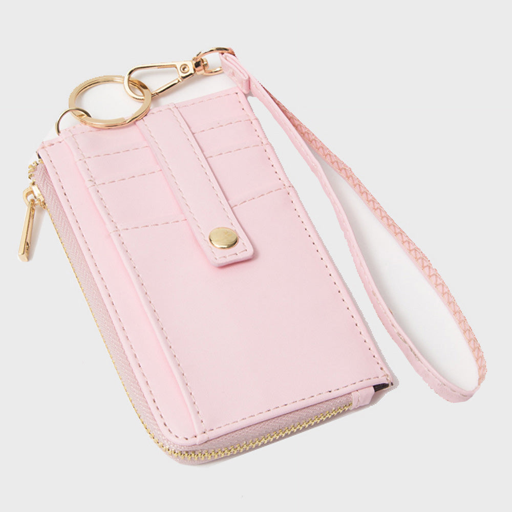 A light pink faux leather phone wallet with a wrist strap, gold-tone hardware, and multiple card slots, shown on a light gray background.