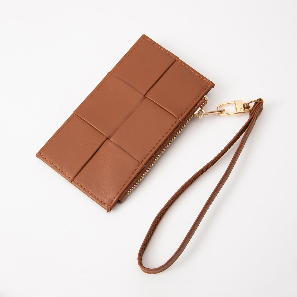 A brown leather wristlet pouch with a woven grid pattern on the front, a gold-tone zipper, and an attached matching leather wrist strap, photographed on a clean white background.