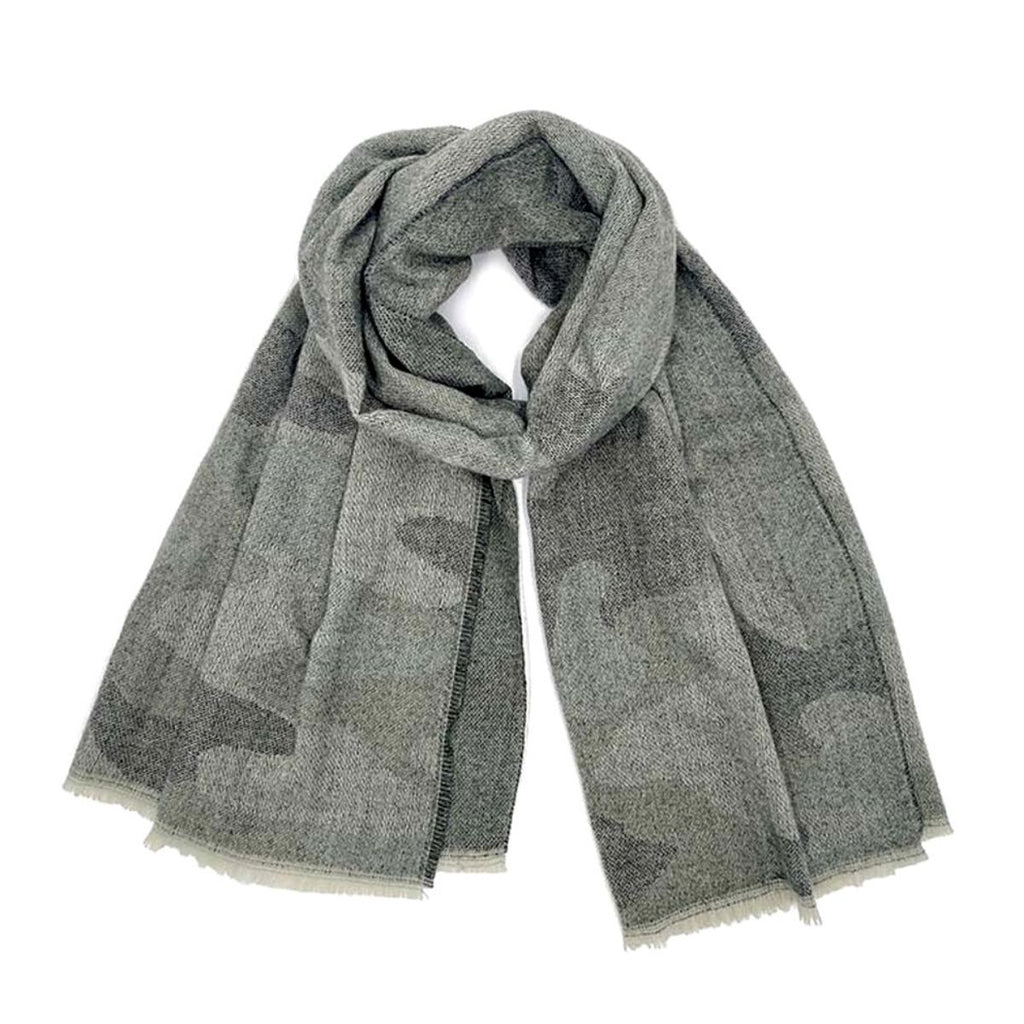 Faded gray camouflage knit scarf loosely looped on a white background, showing its wide shape, charcoal pattern, and pale fringed ends