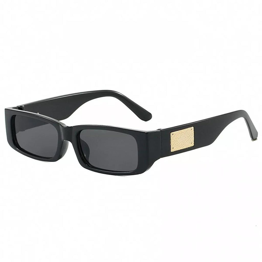 Black rectangular sunglasses with dark gray lenses, wide temples, and a textured gold-tone rectangular accent on a white background