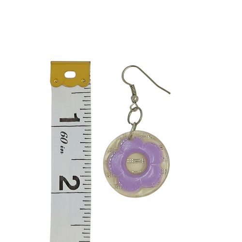 A single dangling earring with a silver-tone fishhook ear wire and a round clear resin pendant featuring a lavender-purple flower motif in the center, shown next to a white measuring tape for scale on a plain light background.