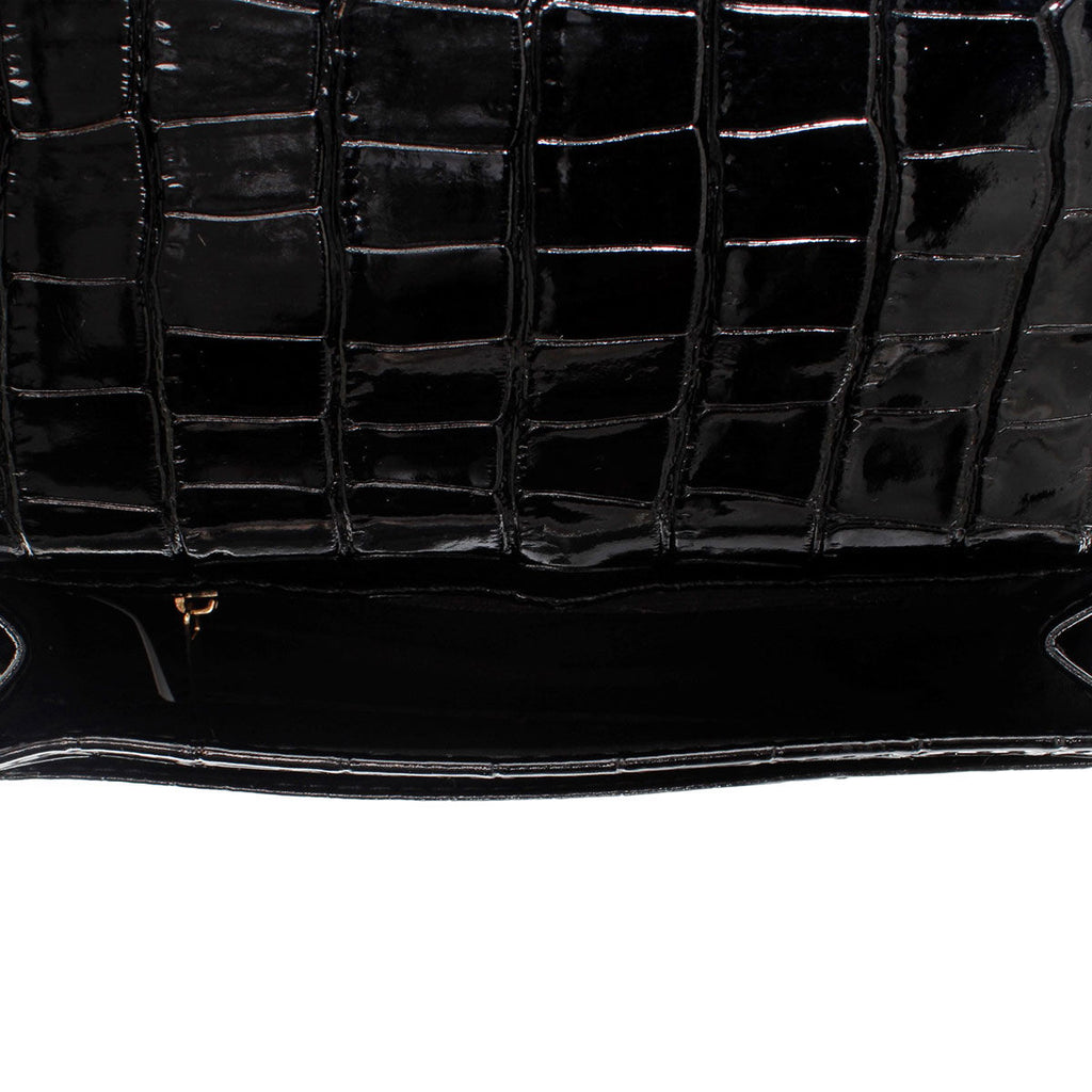 Close-up of the open black croc-embossed bag showing the underside of its flap and dark main compartment