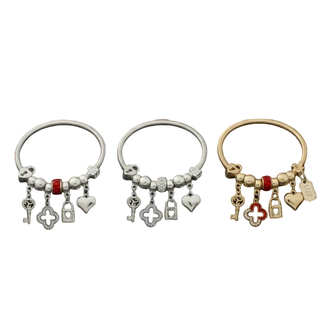 Three metal jump coil stretch bracelets displayed upright on a white background. Left bracelet is silver tone with red rhinestone rondelle bead, center bracelet is silver tone with clear white rhinestone rondelle bead, and right bracelet is gold tone with red rhinestone rondelle bead. Each features dangling key, rhinestone quatrefoil clover, heart lock, and puffy heart charms.