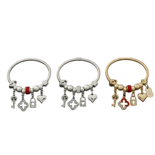 Three metal jump coil stretch bracelets displayed upright on a white background. Left bracelet is silver tone with red rhinestone rondelle bead, center bracelet is silver tone with clear white rhinestone rondelle bead, and right bracelet is gold tone with red rhinestone rondelle bead. Each features dangling key, rhinestone quatrefoil clover, heart lock, and puffy heart charms.