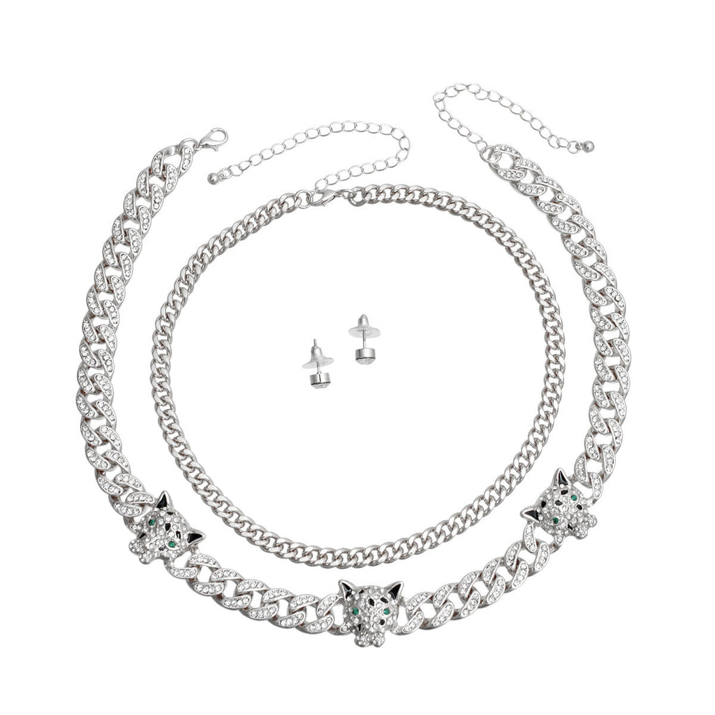 Two-piece silver rhinestone iced Cuban chain necklace set with three leopard head station charms and small round stud earrings, flat lay on white background