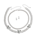 Two-piece silver rhinestone iced Cuban chain necklace set with three leopard head station charms and small round stud earrings, flat lay on white background