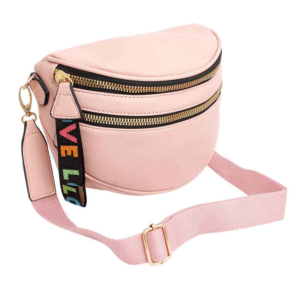 Angled view of the pink sling bag with the wide matching pink canvas strap attached and extended, showing the gold slider adjuster and the rainbow LOVE tab hanging from the gold zippers
