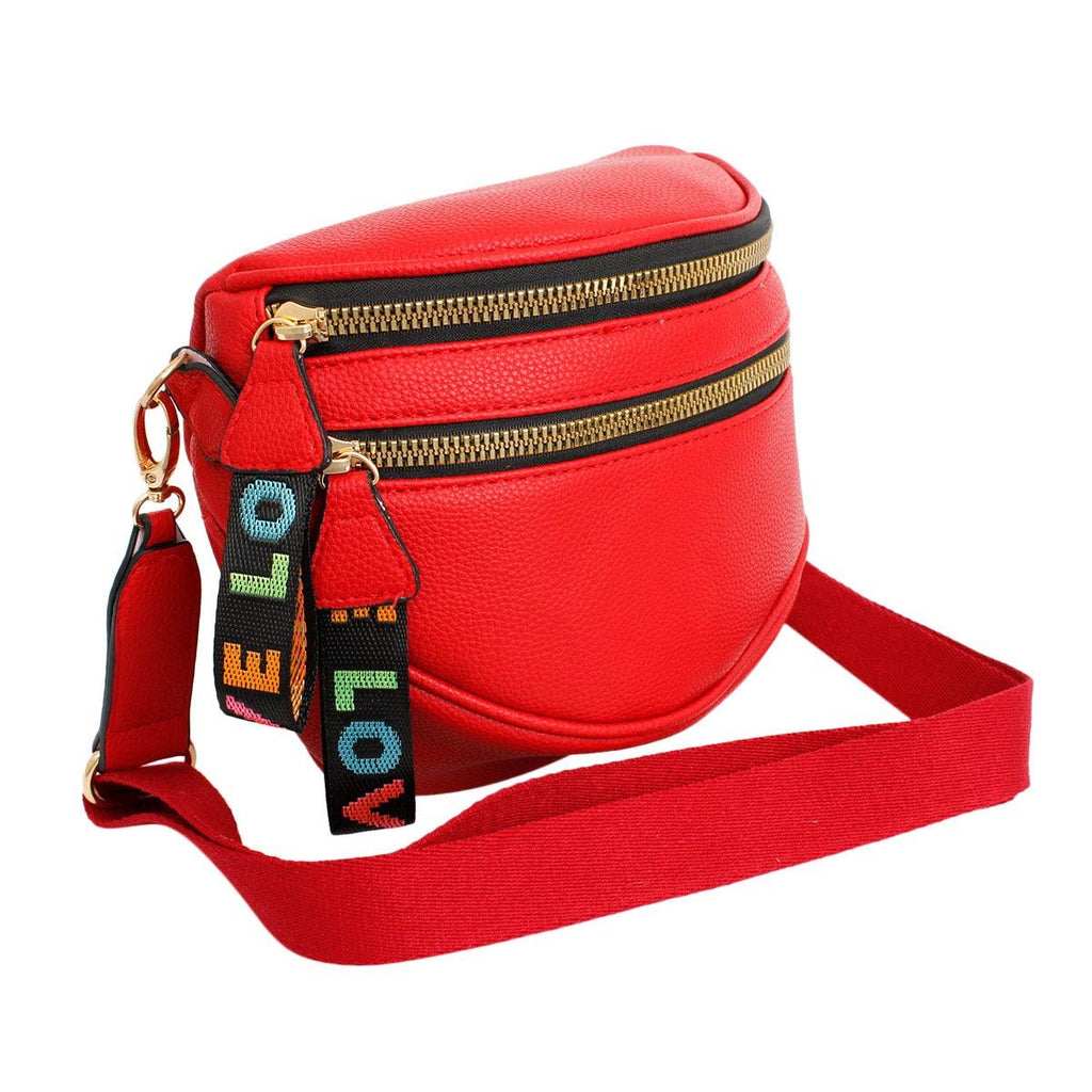 Angled view of the red sling bag with the wide matching red canvas strap attached and extended, showing the gold slider adjuster and both rainbow LOVE tabs hanging from the gold zippers