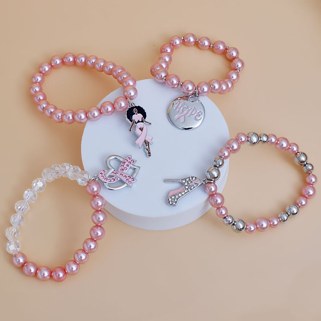 Breast cancer awareness 4-piece light pink pearl stretch bracelet set with Afro woman, Hope disc, pink rhinestone ribbon heart and high heel charms on a white pedestal