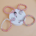 Breast cancer awareness 4-piece light pink pearl stretch bracelet set with Afro woman, Hope disc, pink rhinestone ribbon heart and high heel charms on a white pedestal