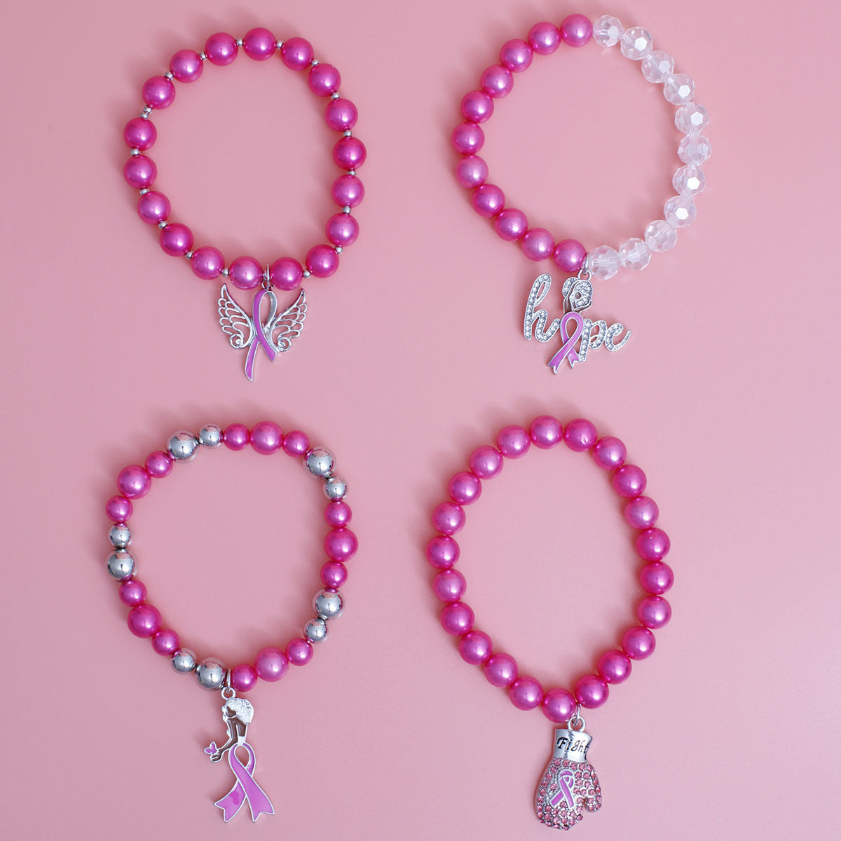 Four pink beaded awareness bracelets arranged in a 2x2 grid on a solid pink background. The bracelets feature various charms: a butterfly ribbon, a silver 'hope' script with a pink ribbon, a silver ribbon with a small star, and a pink and silver boxing glove.