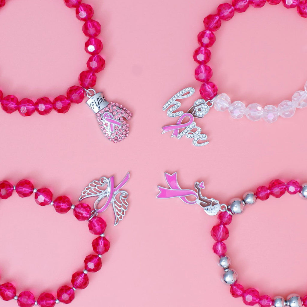 Close-up of pink ribbon charms on fuchsia glass bead bracelets: pink rhinestone Fight boxing glove, rhinestone script Hope, angel wings and woman silhouette