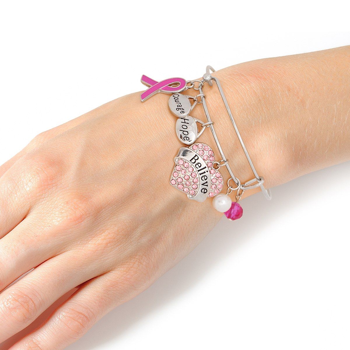 Woman wearing a pink ribbon Believe heart charm bangle on her wrist, showing the pink rhinestone heart, Courage and Hope charms and fuchsia enamel ribbon