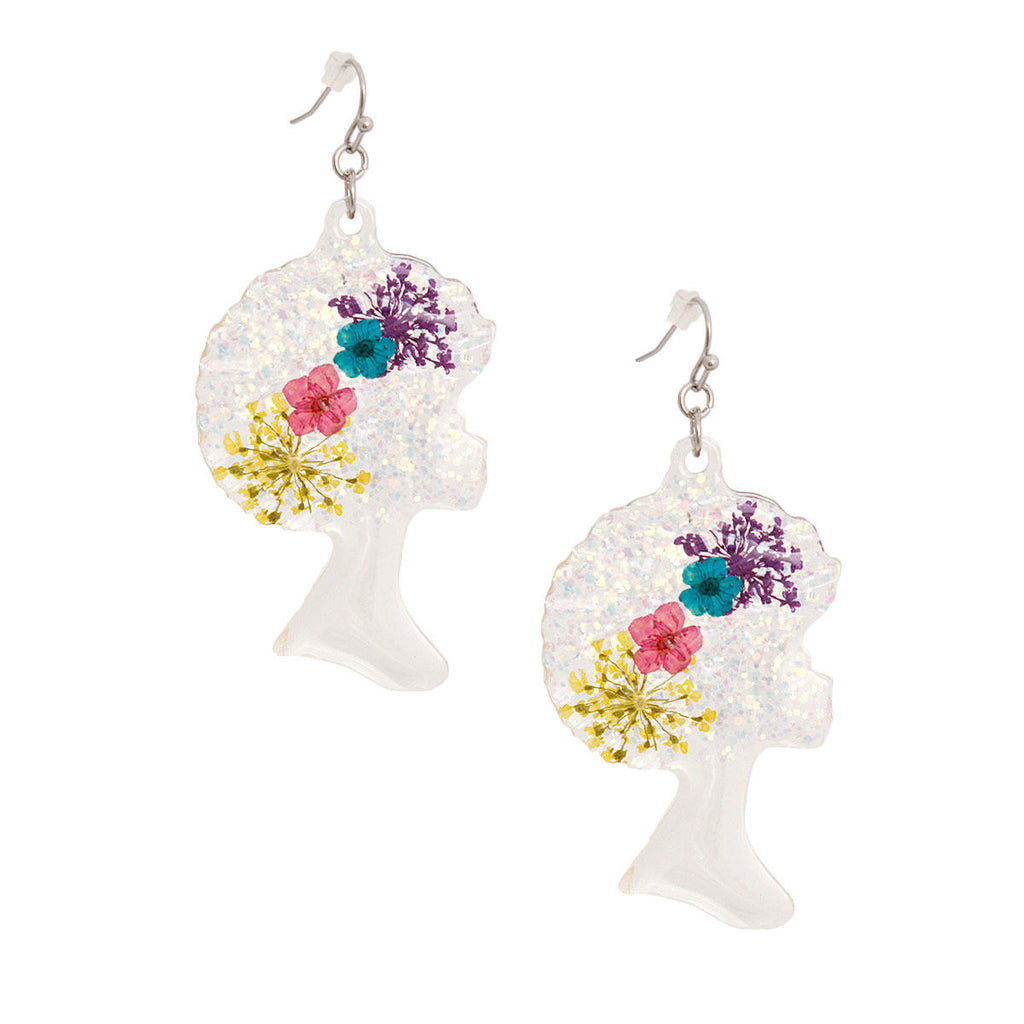 Pair of clear iridescent glitter acrylic Black girl afro silhouette dangle earrings on white background, featuring purple, teal, pink, and yellow multi-color dried flower details embedded in afro shape, with silver fish hook wires