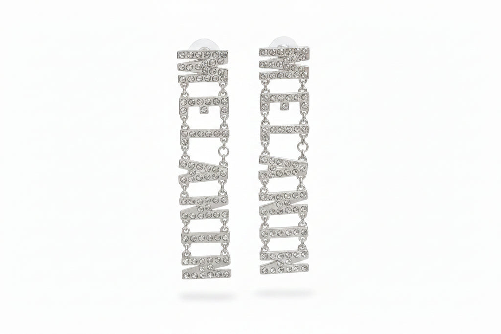 Pair of silver-tone clear pavé rhinestone MELANIN linked letter dangle earrings on white background, showing all seven rhinestone-encrusted letters cascading vertically with small chain links and post backings