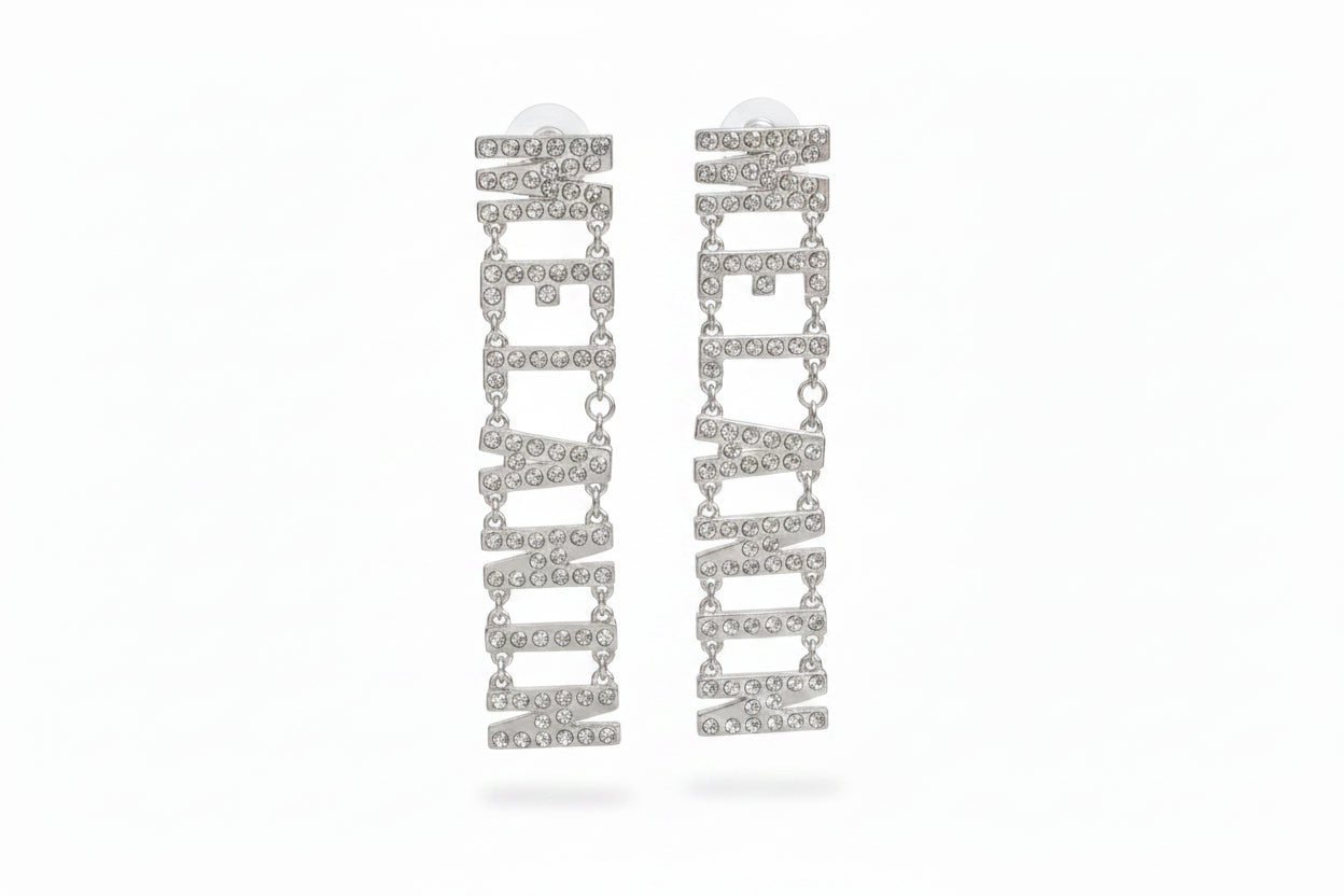 Pair of silver-tone clear pavé rhinestone MELANIN linked letter dangle earrings on white background, showing all seven rhinestone-encrusted letters cascading vertically with small chain links and post backings