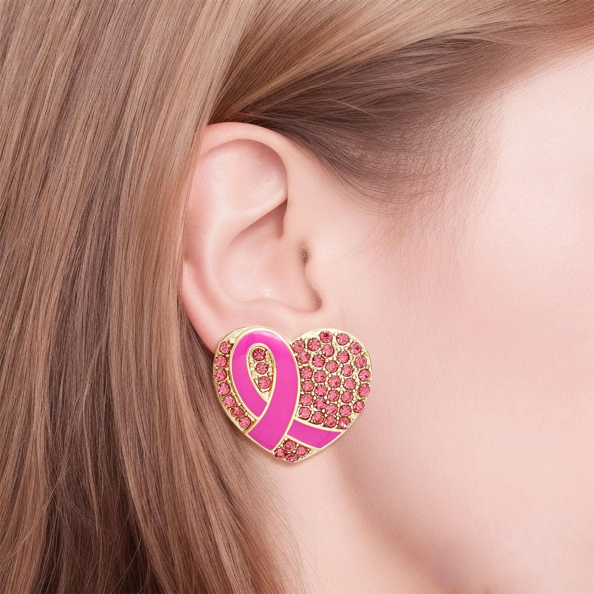 Woman wearing a pink ribbon heart rhinestone gold stud earring, showing the fuchsia enamel awareness ribbon and sparkling pink pavé stones