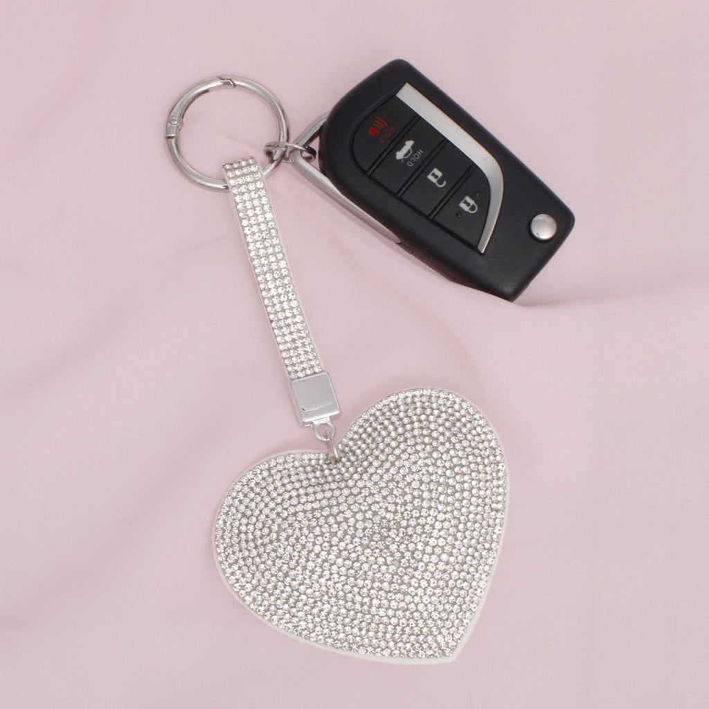 Full rhinestone-covered white padded heart bag charm keychain with multi-row crystal strap, shown attached to a car key fob with silver split keyring on pink background