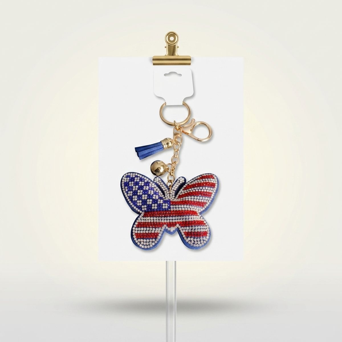 Patriotic butterfly bag clip keychain with American flag rhinestone detail, blue mini tassel, and gold lobster clasp on white display card